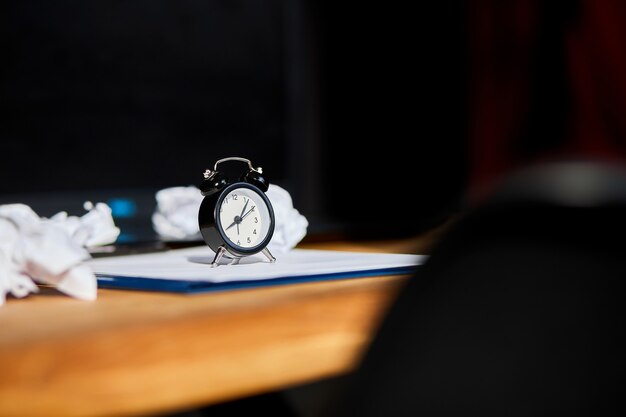 Modern workplace, wooden office desk in hardlight, sunligt with clock, sheet of paper