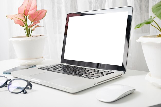 Modern workspace mock up laptop computer blank white screen eyeglasses and smartphone