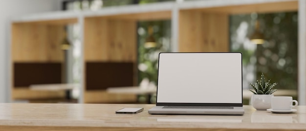 Modern workspace with laptop mockup over blurred cafe coworking space in background