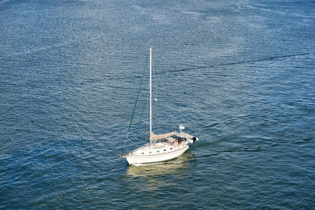 現代のヨットや帆船や船舶は、美しい海の晴れた日に青い海や海の水面をモーターで移動します