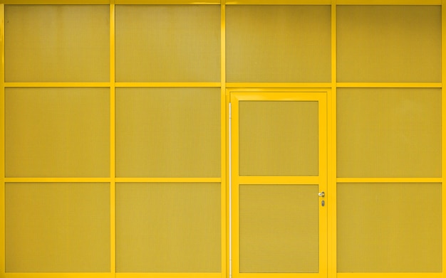 Modern yellow building exterior with metallic facade and door