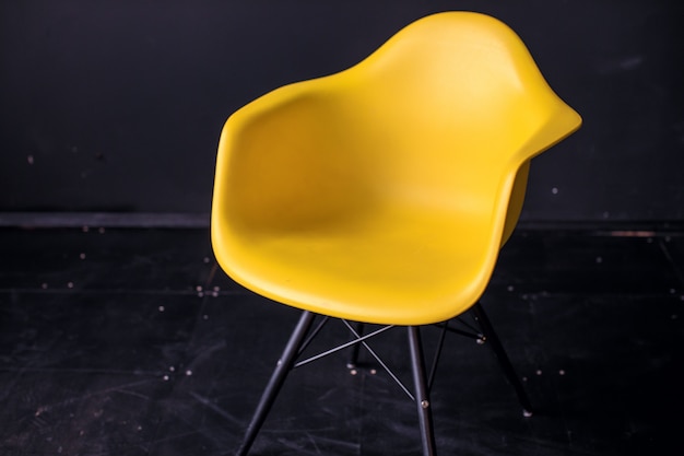 Modern yellow chair in black room interior parquet wood floor.