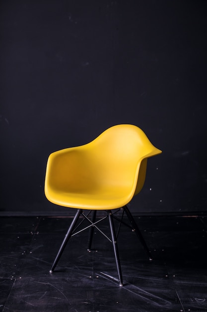 Modern yellow chair in black room interior