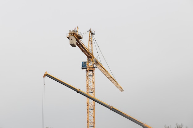 Modern yellow construction cranes above blue sky