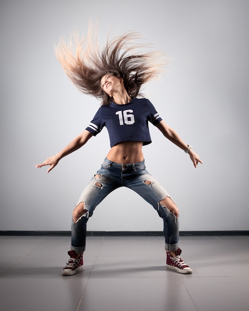 Modern young beautiful dancer posing on a studio background