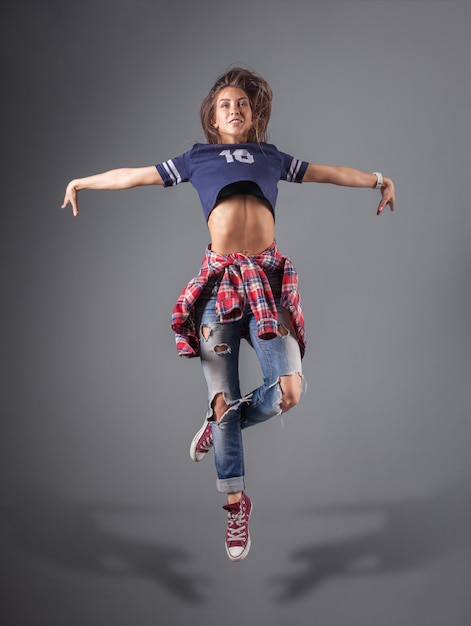 Modern young beautiful dancer posing on a studio background