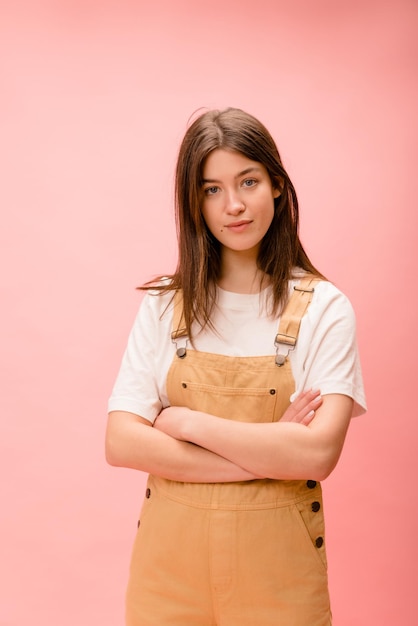 Modern young caucasian brunette woman with folded hands looks at camera on pink background Lifestyle female beauty concept