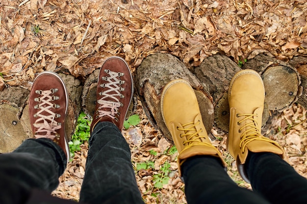 Modern young couple in hiking boots standing fallen autumn leaves in the forest