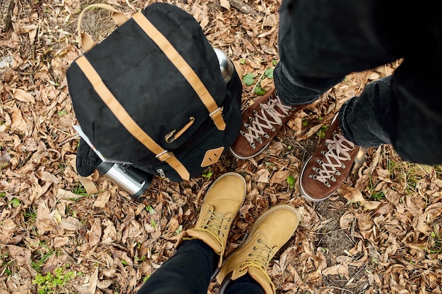 Photo modern young couple in hiking boots standing in the wood with travel bag