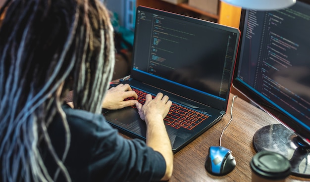 Modern young female programmer is writing program code on a laptop at home