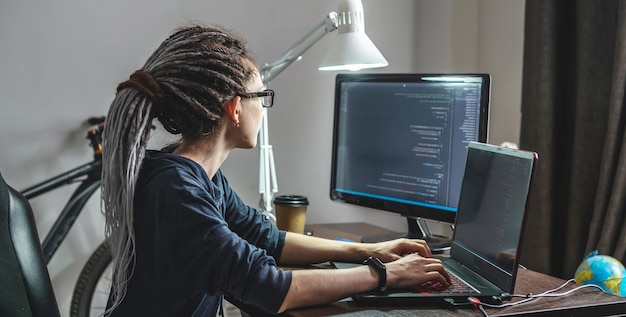 현대 젊은 여성 프로그래머는 집에서 노트북에 프로그램 코드를 작성하고 있습니다