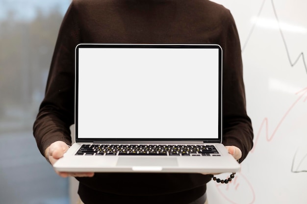 Posto moderno dello spazio della copia dello schermo in bianco del computer portatile della tenuta del giovane per il modello pubblicitario