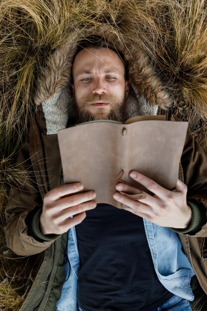 Giovane moderno che si trova sull'erba che legge un libro