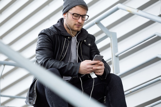 Современный молодой человек, используя свой мобильный телефон на улице.
