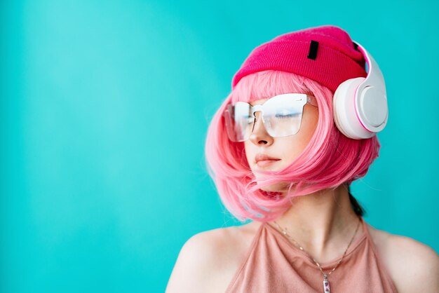 Modern youth culture portrait of a girl with a short pink haircut on a blue background