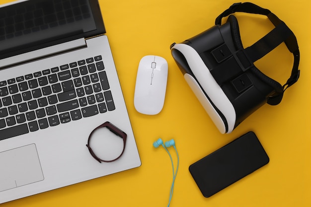 modern youth gadgets and devices on yellow background. top view. flat lay