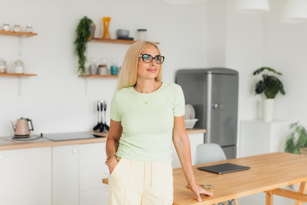 Moderne aantrekkelijke vrouw van middelbare leeftijd poseren in de keuken thuis