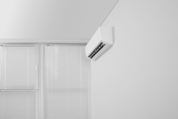 Moderne airconditioner op witte muur binnenshuis lage hoekweergave Ruimte voor tekst