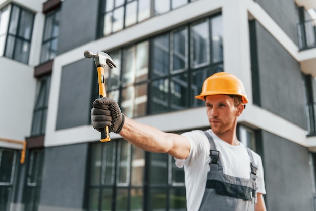 Moderne buitenkant Jonge man aan het werk in uniform bij de bouw overdag