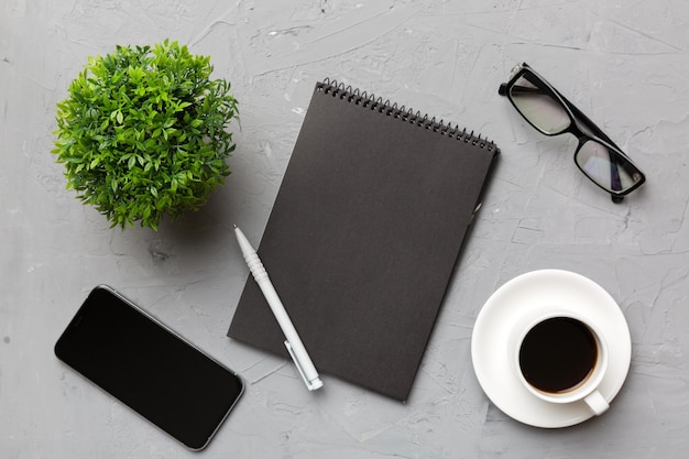 Moderne bureautafel met notebook-smartphone en andere benodigdheden met kopje koffie Lege notebookpagina voor u ontwerp Bovenaanzicht plat lag