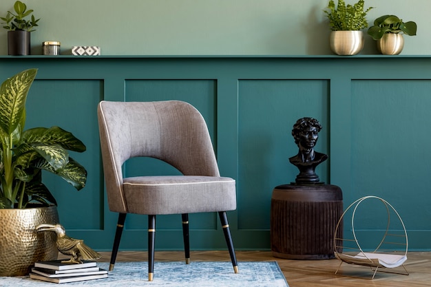 Moderne compositie van woonkamer met design grijze fauteuil, gouden pot met mooie plant, bruine poef en elegante persoonlijke accessoires. Wandbekleding met plank. Stijlvolle huisstaging. Sjabloon.