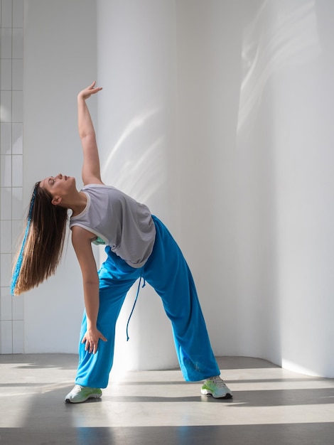 Moderne dans stijlvolle brunette in flodderige blauwe broek dansen in jazzfunk-stijl