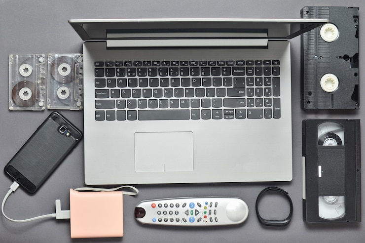 Foto moderne digitale gadgets, opslagmedia, devaysy en verouderde analoge media-apparaten op een grijze papieren achtergrond. bovenaanzicht plat liggen.
