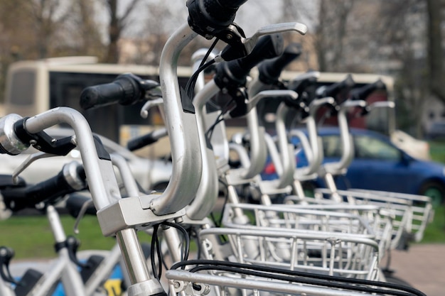 Moderne elektrische huurfietsen staan op een rij tijdens het opladen op een heldere dag met een selectieve focus op de verticale betaalterminal met een mockup van informatieve of een tijdelijke aanduiding voor een advertentiebanner erop