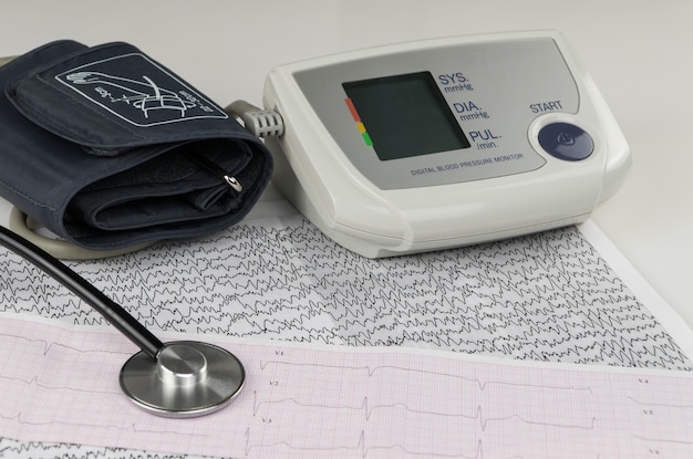 Foto moderne elektrische tonometer en een stethoscoop op een cardiogram-grafiek. huishoudelijke bloeddrukmeter