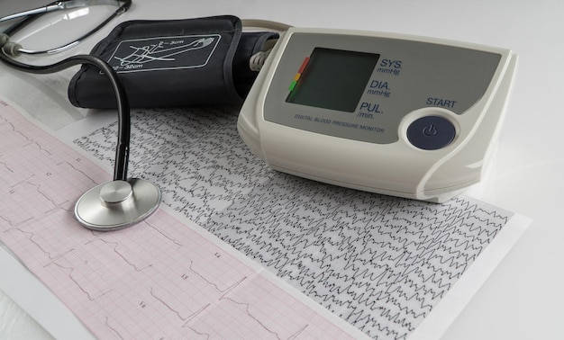 Moderne elektrische tonometer en een stethoscoop op een cardiogram-grafiek. huishoudelijke bloeddrukmeter