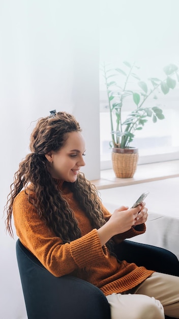 Moderne externe werker gelukkige jonge vrouw die smartphone en laptop gebruikt voor e-learning en werken op afstand bij