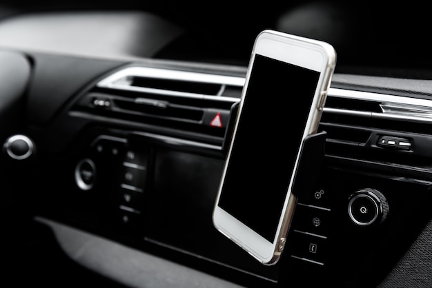 Moderne gadget voor smartphoneapparaten gemonteerd op telefoonhouder op autodashboard