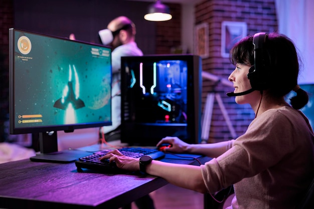 Moderne gamer die online multiplayer-videogames streamt, wordt op de computer gespeeld en geniet van een schietspel-toernooi. Vrouwelijke streamer die actie-rpg-spelcompetitie speelt op pc-monitor.