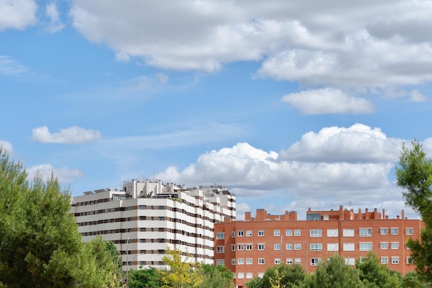 Foto moderne gebouwen gezien door het levendige groen onder een bewolkte levendige hemel in madrid spanje