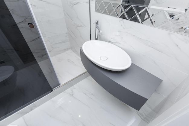 Moderne grijze badkamer met wastafel en douche betegeld met witmarmeren tegels
