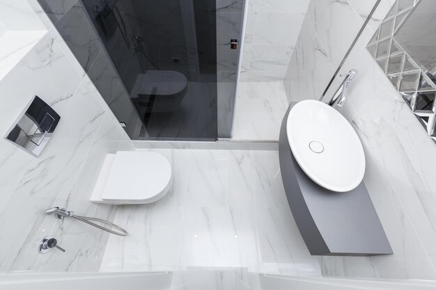 Moderne grijze badkamer met wastafel en douche betegeld met witmarmeren tegels