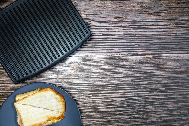 Moderne grillmaker met broodje gegrilde kaas op houten tafelblad weergave kopie ruimte