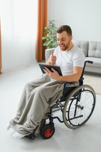 Moderne jonge gehandicapte man in rolstoel met videogesprek