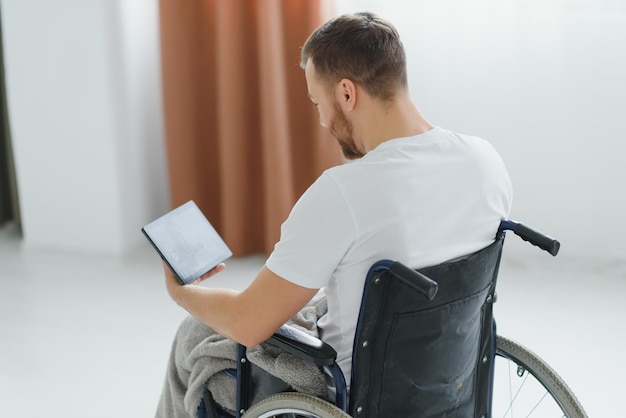 Moderne jonge gehandicapte man in rolstoel met videogesprek