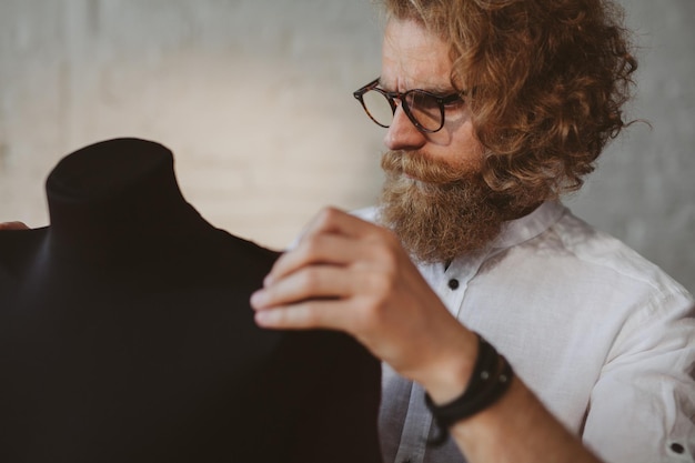 moderne jonge kledingontwerper in het werkproces, een kledingontwerper met lang haar en baard