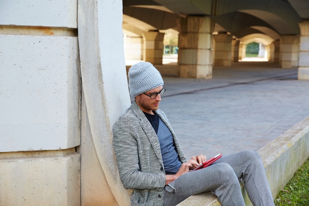 Moderne jonge man met tablet pc onder een brug