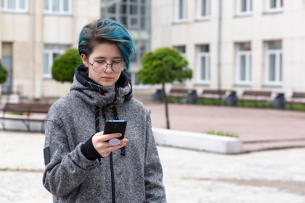 Moderne jonge meisje kijkt naar het scherm van de smartphone op straat Onlinecommunicatie