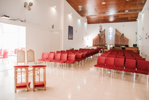 Moderne katholieke kerkzaal met rode stoelen en orgel