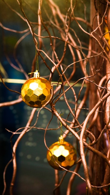 Moderne kerstdecoratie met gouden ballen en natuurlijke takken in plaats van een kerstboom.