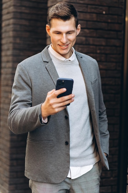 Moderne knappe glimlachende man die door de straat loopt en aan de telefoon praat