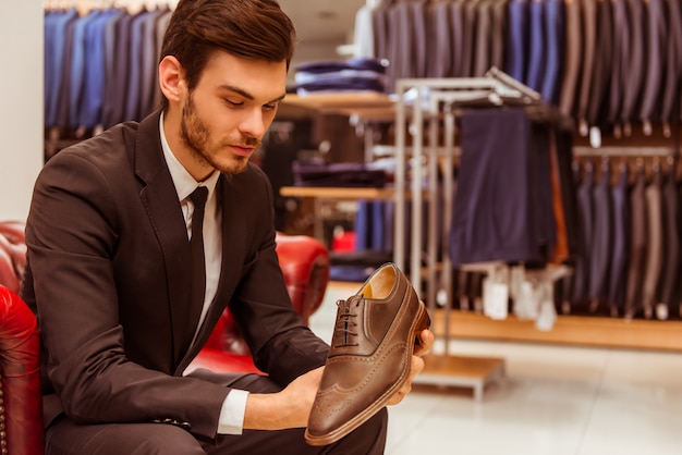 Moderne knappe zakenman die klassieke schoenen houdt.