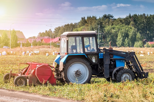 Moderne landbouwtractor op wielen met oogstapparatuur op een veld