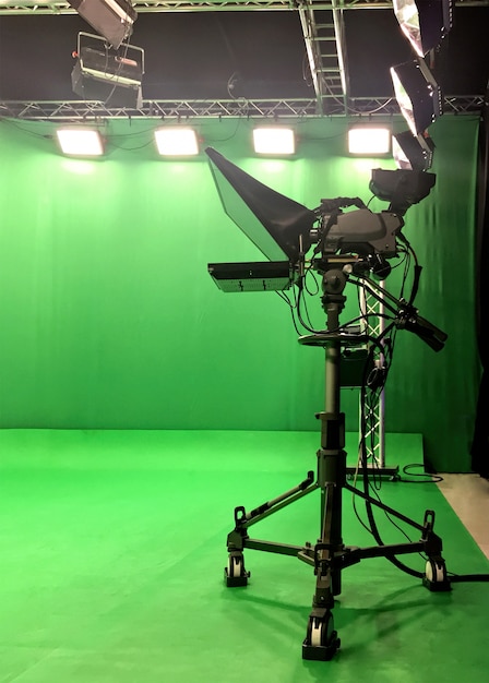 Moderne lege groene video-opname- en omroepstudio met tv-kanaal led scherm en metalen stands, tekstprompter, lampjes aan