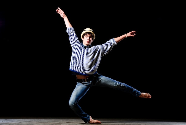 Moderne mannelijke danser in balletstijl presteert op een hoog verlicht podium.