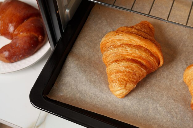 Moderne mini-elektrische oven met vers gebakken croissants in de keuken